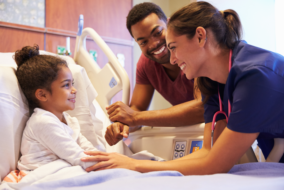 A child in a hospital bed with a parent and nurse